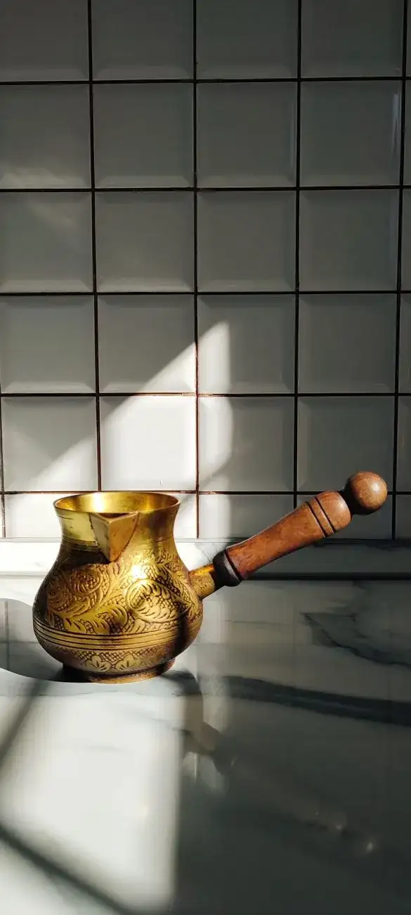 An elegant coffee pot next to a steaming mug