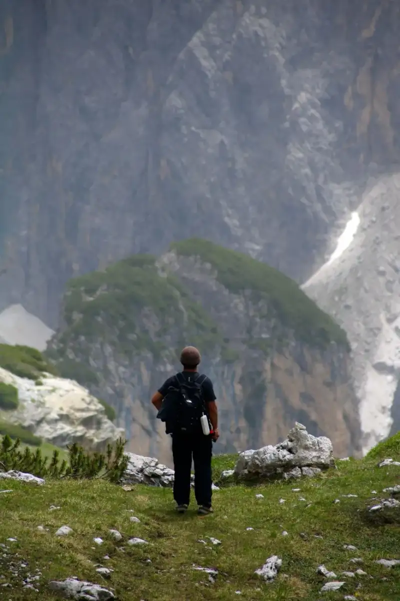 Hiker on a trail with Dolomites peaks in the background