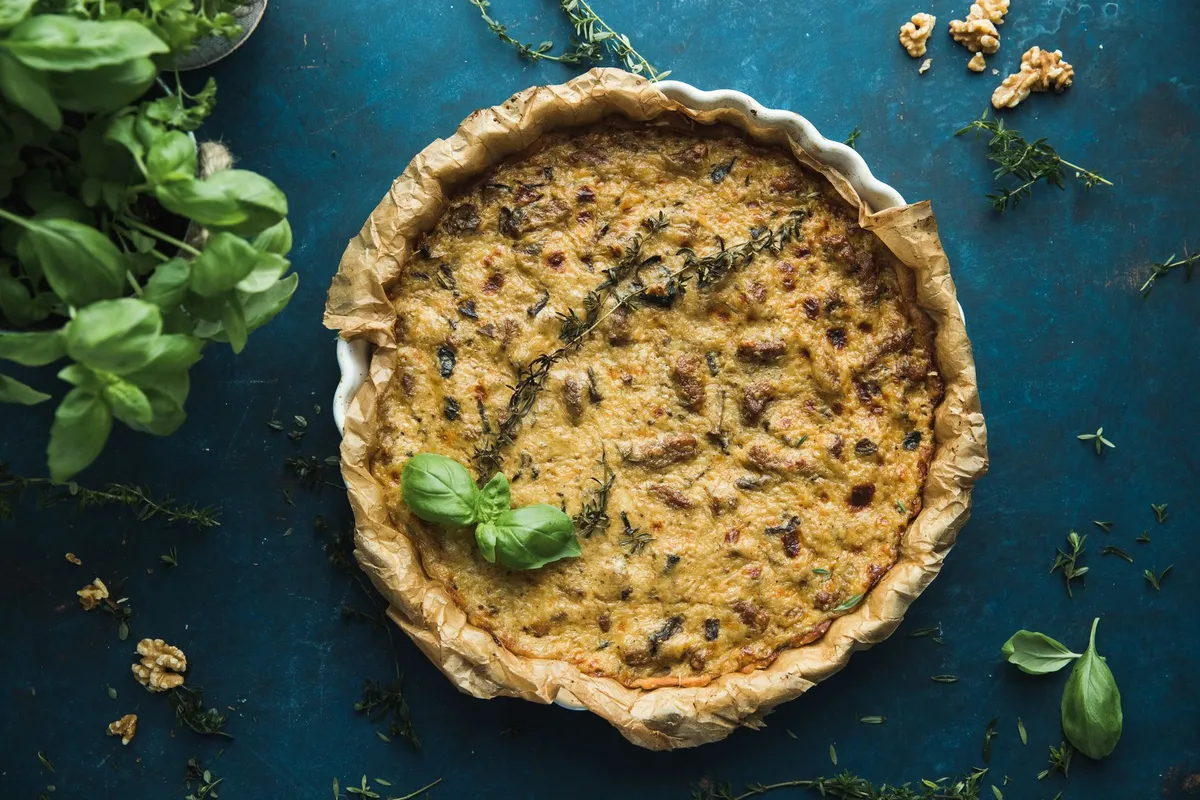 A rustic, steam-filled cast iron skillet containing a vibrant lentil-based shepherd's pie.
