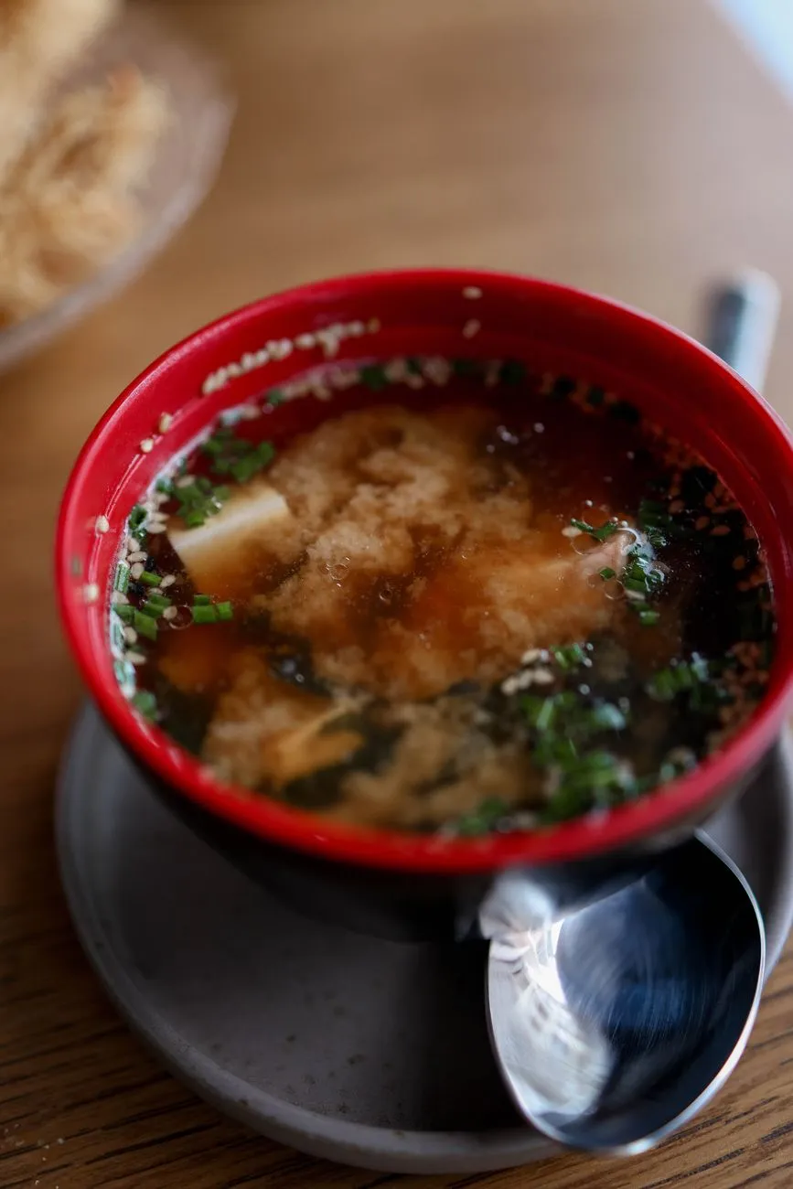 A steaming bowl of miso soup with tofu and seaweed, illustrating the deep, savory essence of umami