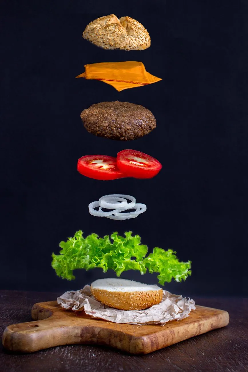 A modern deconstructed burger with umami-rich components like caramelized onions, blue cheese, and a soy-glazed patty