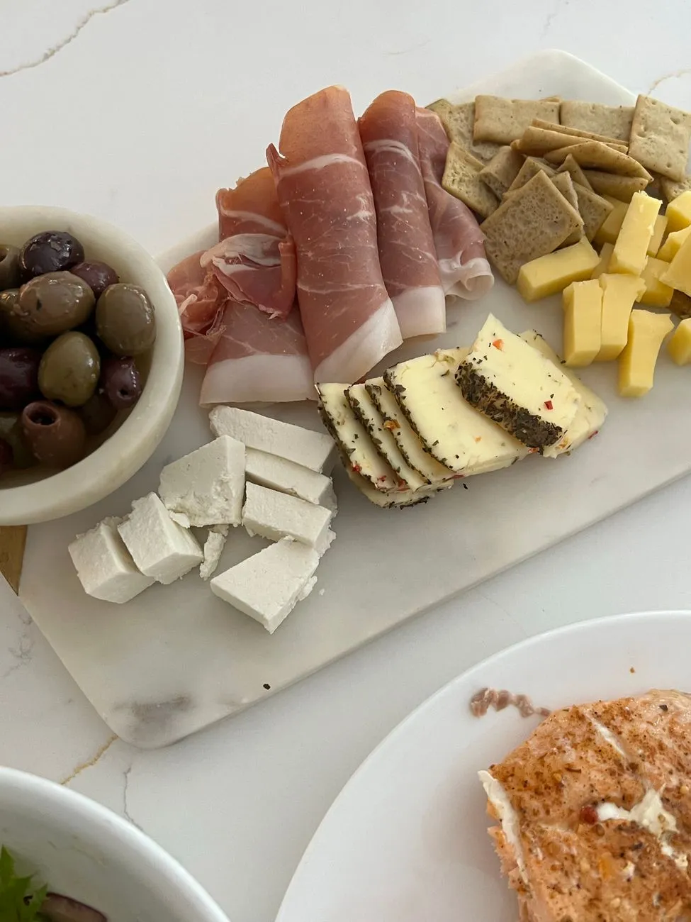 A spread of umami-rich dishes: a charcuterie board with aged cheeses, cured meats, olives, and roasted nuts