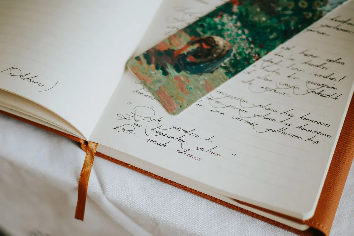 A traveler sitting on a stone wall overlooking a misty valley, writing in a leather journal