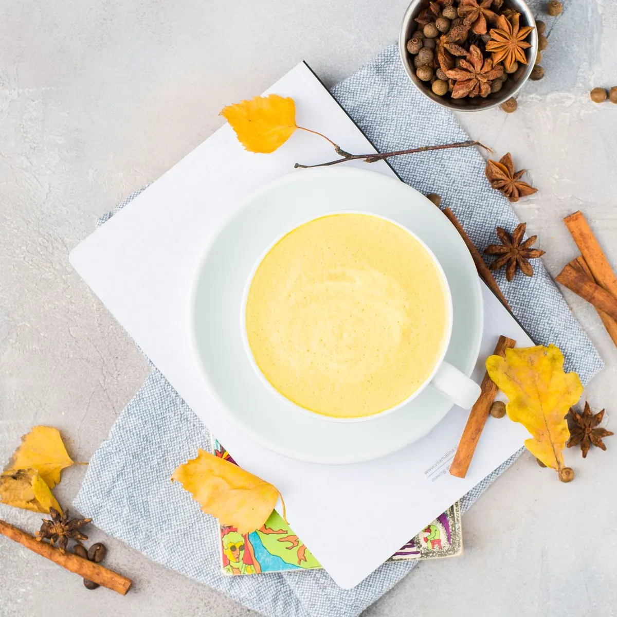 A close-up of a cup of chai with ginger slices, cinnamon sticks, and a sprinkle of turmeric, highlighting its healthful ingredients