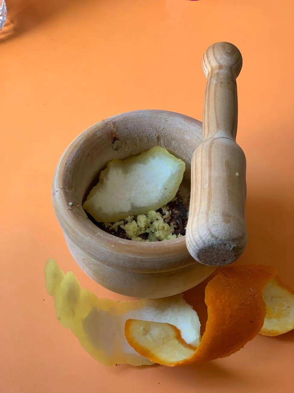 A wooden table set with ingredients for homemade chai—loose black tea, spices, milk, sugar, and a mortar and pestle