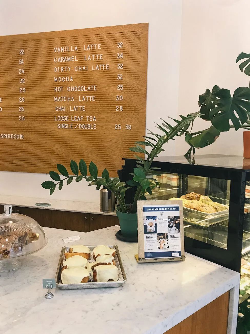 A modern café interior with a chalkboard menu listing various chai flavors, including lavender chai and matcha chai