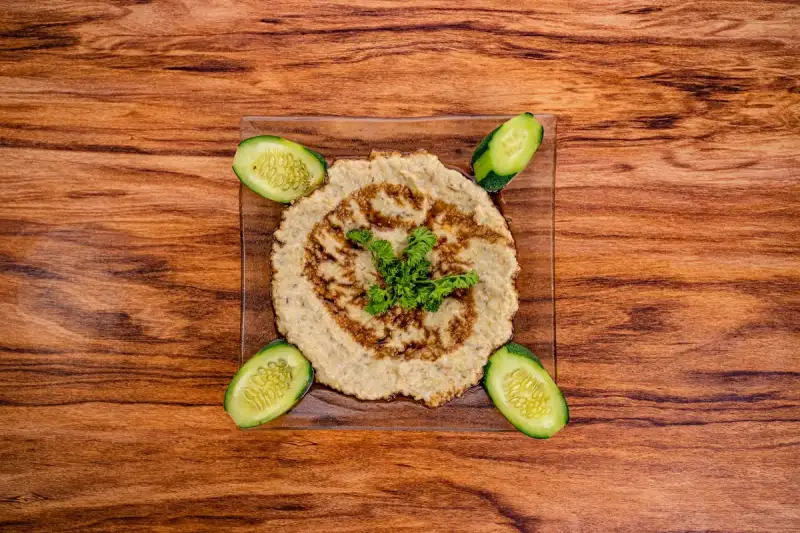 A vibrant bowl of hummus garnished with za'atar, olive oil, and fresh herbs, ready to be enjoyed.