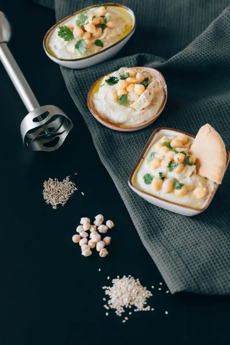 A food processor blending chickpeas, tahini, lemon juice, and garlic into a creamy, smooth hummus.