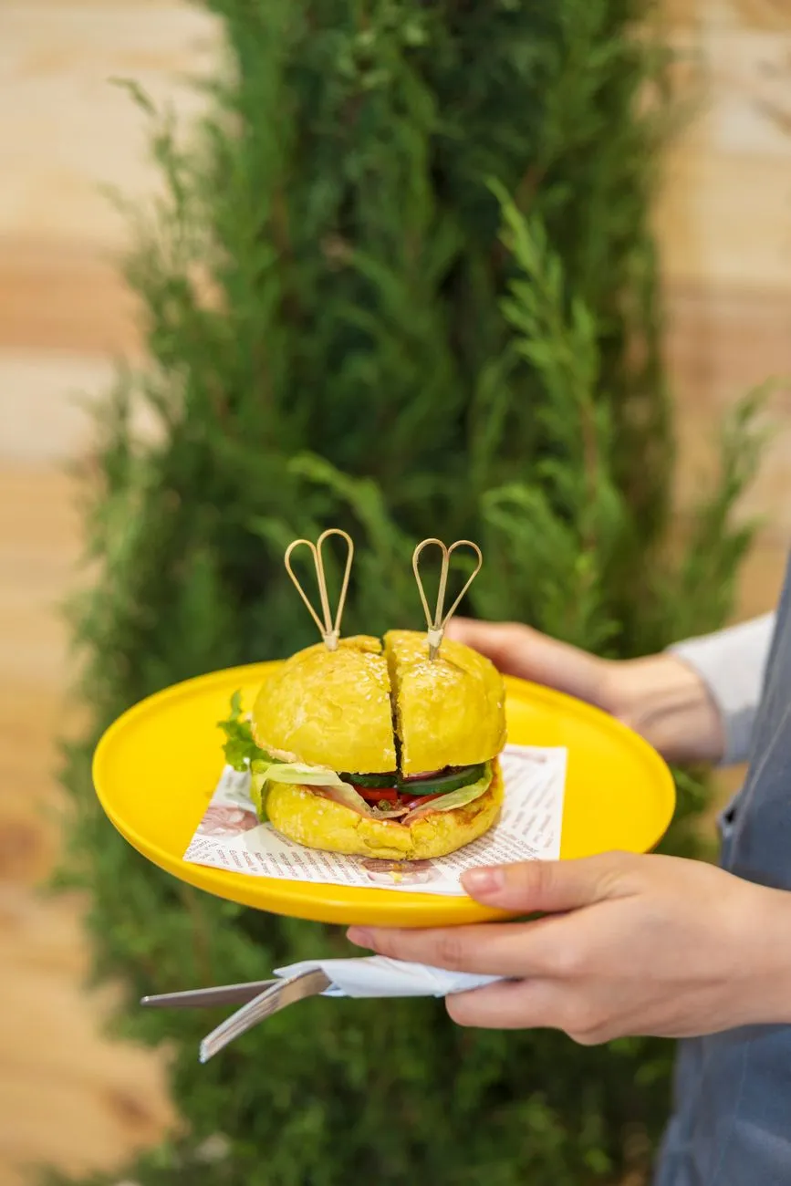A plant-based burger with lettuce, tomato, and vegan cheese on a sesame seed bun