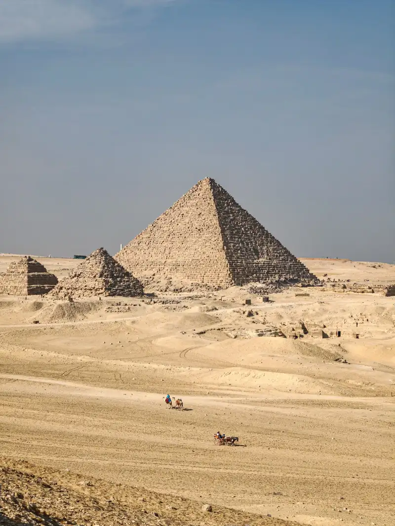 High aerial drone view of the complete Giza pyramid complex, clearly showing Khufu's Great Pyramid, the causeway, temples outlines, and surrounding mastaba fields, desert background, clear sky