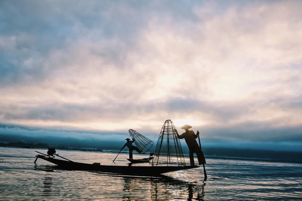 A lone Intha fisherman casting his net at sunrise