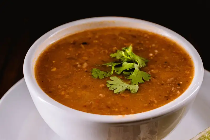 A steaming bowl of comforting lentil stew topped with fresh dill and black pepper