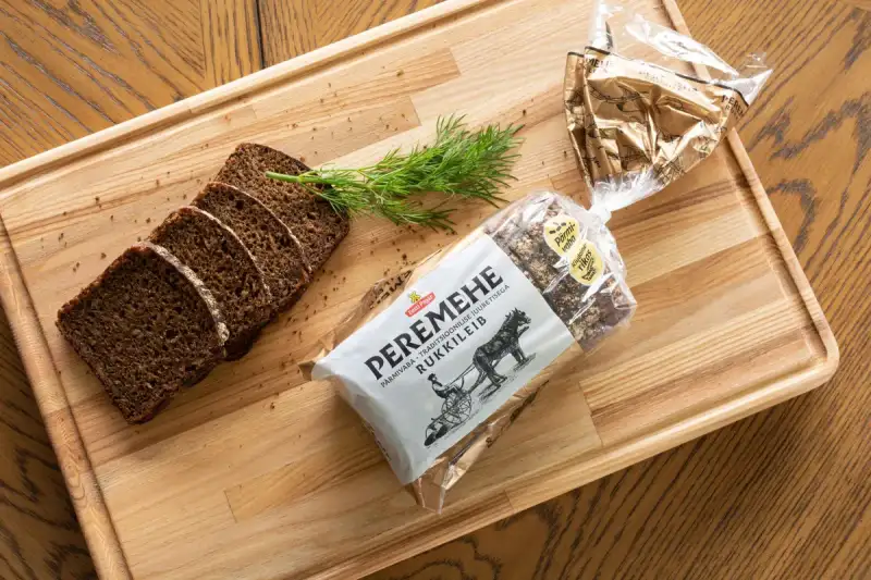 A rustic table setting featuring a warm bowl of stew alongside a slice of dark German rye bread