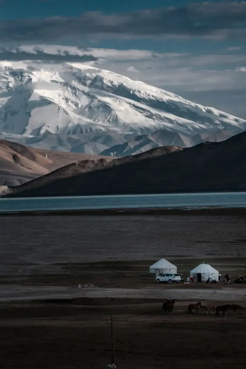 A traditional Kyrgyz yurt camp set against the backdrop of snow-capped mountains