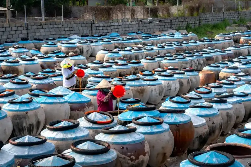 Modern artisanal fish sauce production, close-up of fermentation vats, umami focus, chef preparing with garum