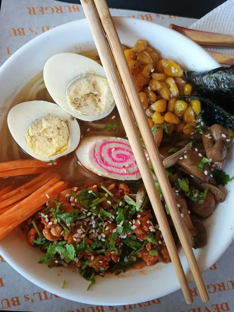 A bowl of ramen topped with a sprinkle of MSG, with chopsticks resting on the side