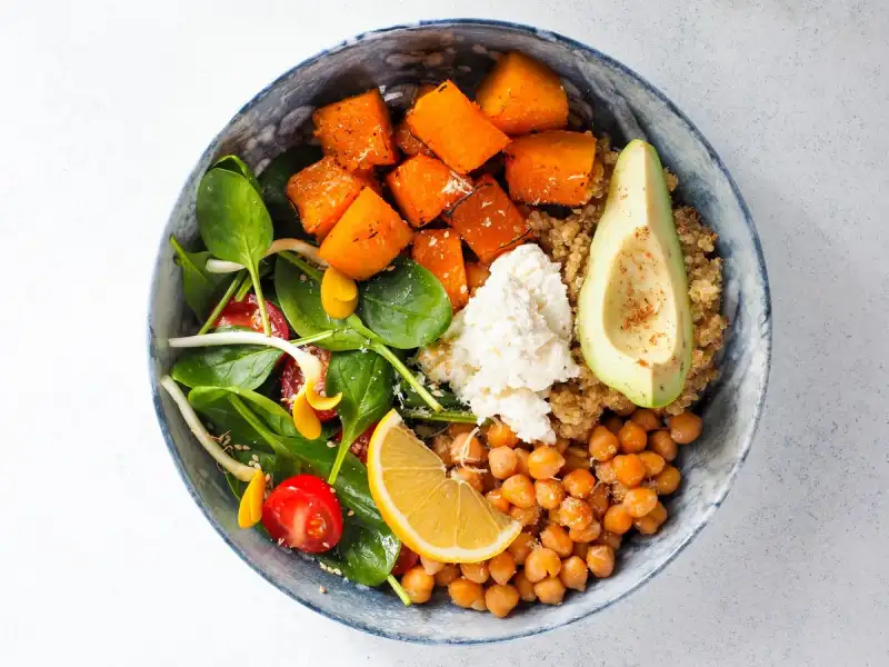 A vibrant Buddha bowl filled with roasted vegetables, tahini sauce, and sprinkled with nutritional yeast
