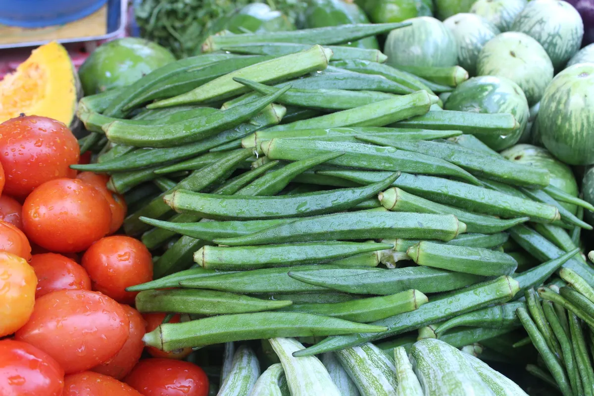 Fresh raw okra pods resting on a wooden cutting board