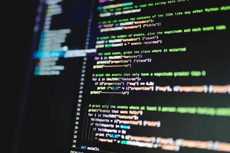 A developer's dual monitor setup displaying complex code and an AI dashboard