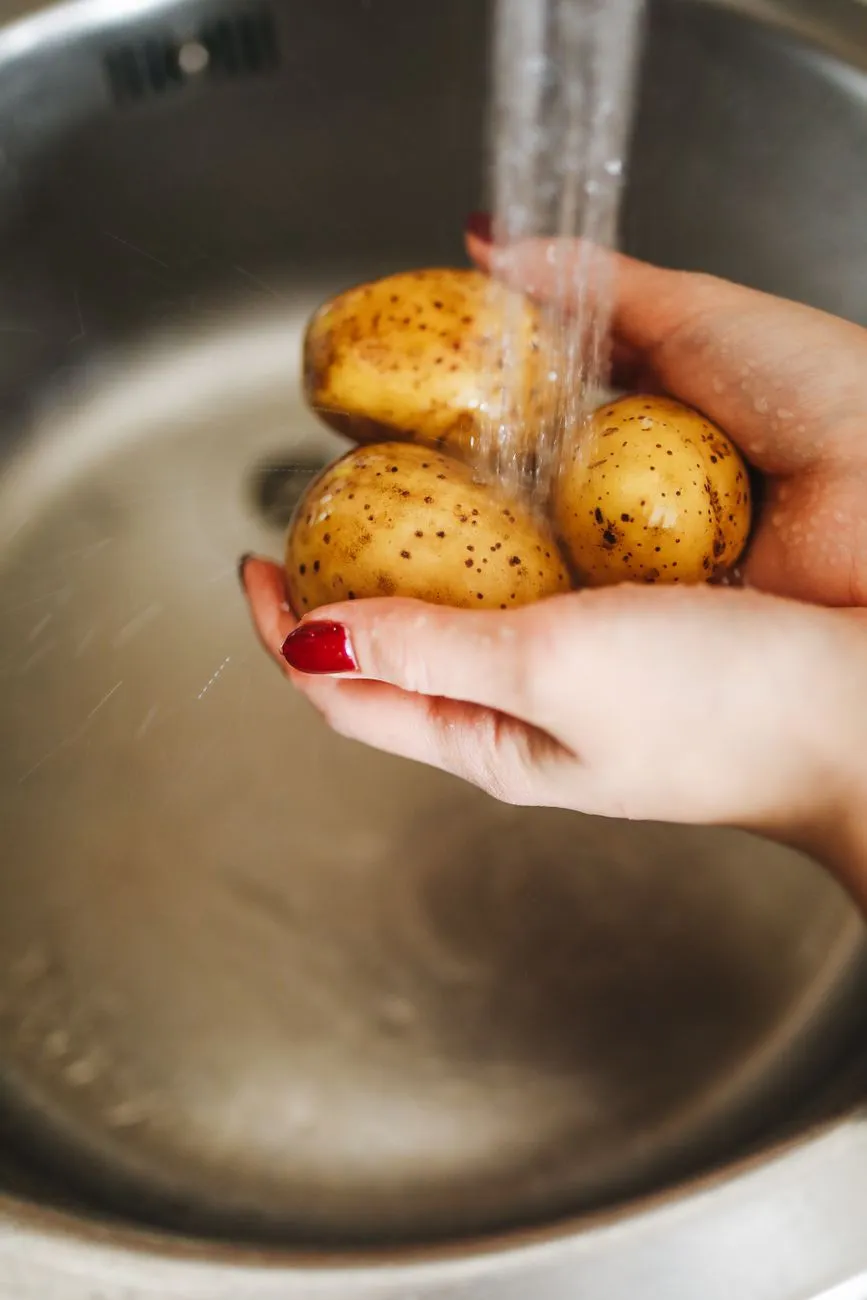 Vegetable peels being rinsed under running water