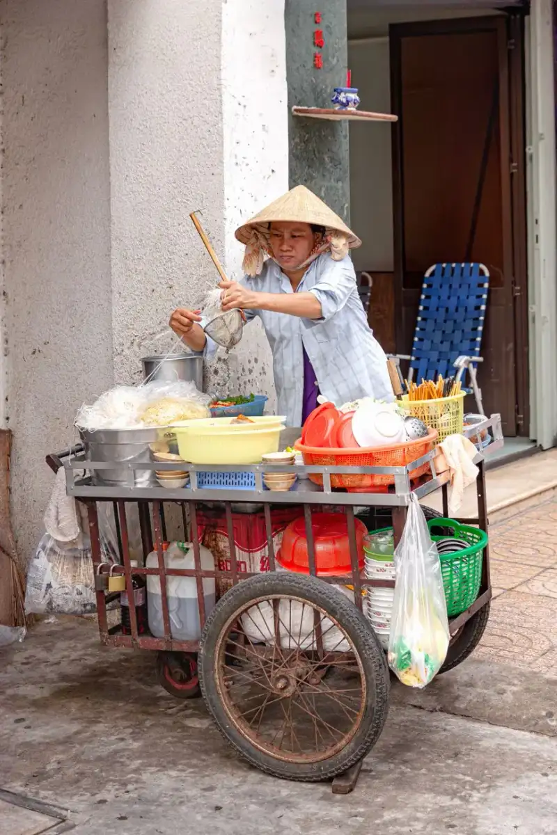 A bustling Hanoi street at dawn with vendors preparing pho