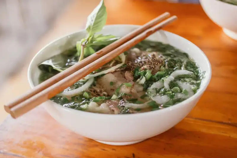 A close-up of a pot of simmering pho broth with spices