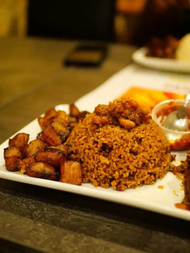 A bowl of waakye, garnished with onions and tomatoes