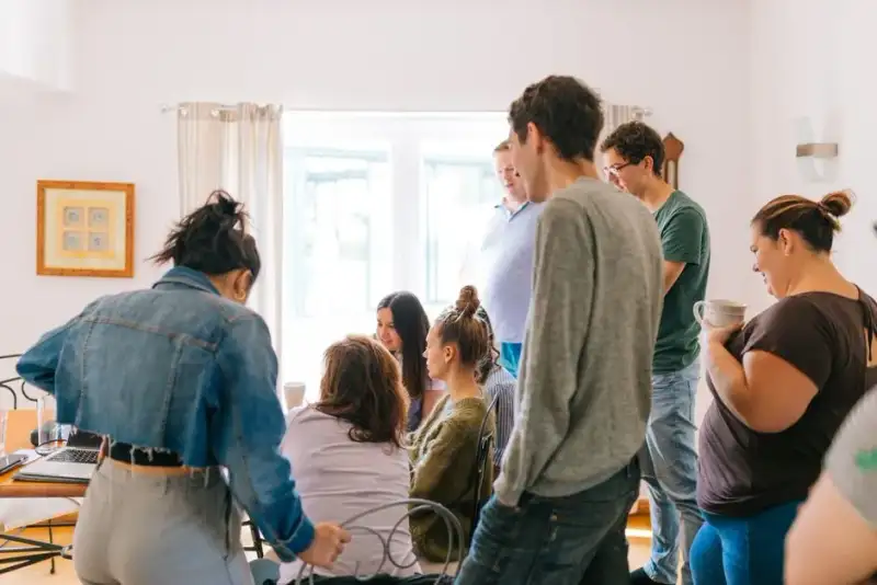 A small group of people clandestinely reading a handwritten manuscript in a dimly lit Soviet-era apartment, sharing a moment of intellectual defiance and solidarity.