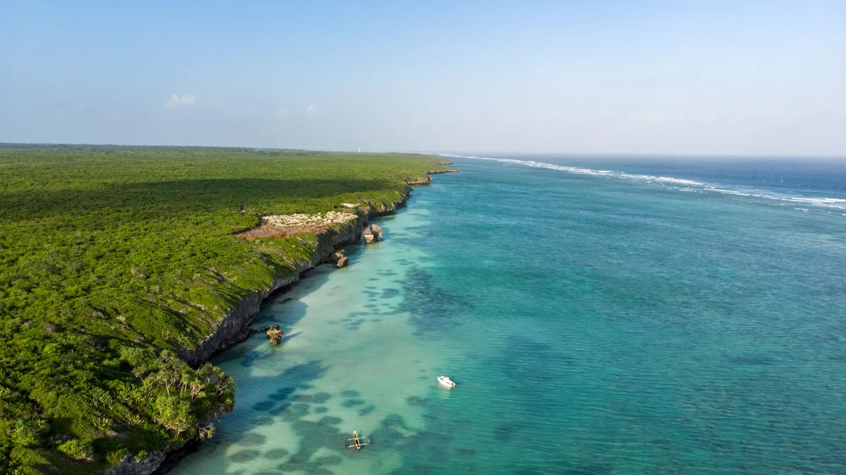 A secluded beach with turquoise water and white sand in Zanzibar, viewed from a cliff